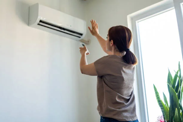 Homeowner reaching up to adjust a wall-mounted ductless unit