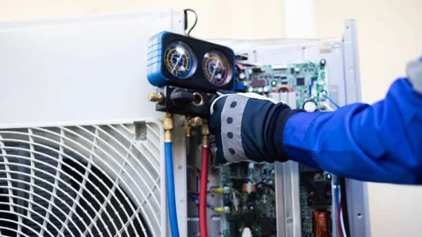 Gloved hand and gauge set at an outdoor unit with the control board exposed